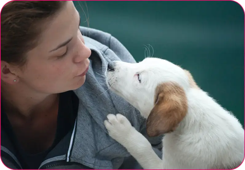 A woman is kissing her dog on the nose.